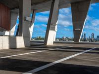 an empty parking garage with multiple columns on one side and sky scrapes behind it