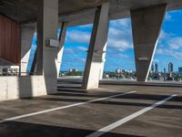 an empty parking garage with multiple columns on one side and sky scrapes behind it