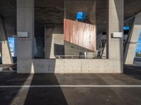 a skateboarder performing a trick in a parking garage, on the edge of an overpass