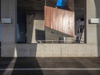 a skateboarder performing a trick in a parking garage, on the edge of an overpass