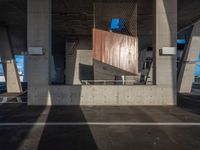 a skateboarder performing a trick in a parking garage, on the edge of an overpass