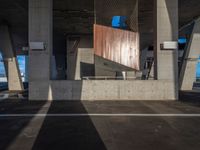 a skateboarder performing a trick in a parking garage, on the edge of an overpass