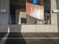 a skateboarder performing a trick in a parking garage, on the edge of an overpass