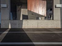 a skateboarder performing a trick in a parking garage, on the edge of an overpass