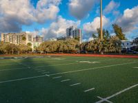 the green turf on a soccer field in an urban setting with high rise buildings in the background