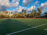 the green turf on a soccer field in an urban setting with high rise buildings in the background