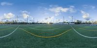 a sports field with green grass and yellow lines on it, with clouds in the sky