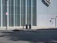 two trash can't sit next to an entrance to a building with some large sculpture on the wall