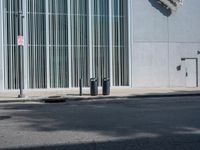 two trash can't sit next to an entrance to a building with some large sculpture on the wall