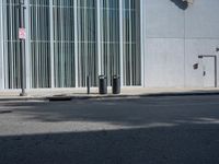 two trash can't sit next to an entrance to a building with some large sculpture on the wall