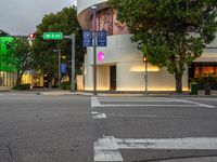 a stoplight is on at an intersection next to an urban shopping center at dusk