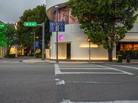 a stoplight is on at an intersection next to an urban shopping center at dusk