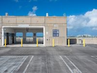 a parking garage with several parking gates in a lot with blue sky and cloud cover