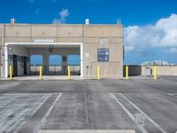 a parking garage with several parking gates in a lot with blue sky and cloud cover