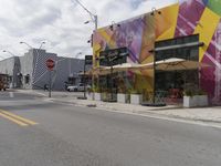 a city street with cars, street lights, and a stop sign in front of some store fronts