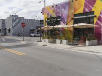 a city street with cars, street lights, and a stop sign in front of some store fronts