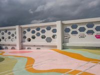 a white fence with colorful hexagons on it at the top of a hill