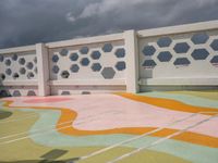 a white fence with colorful hexagons on it at the top of a hill