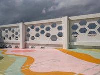 a white fence with colorful hexagons on it at the top of a hill