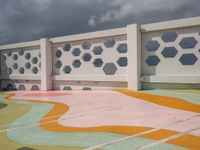 a white fence with colorful hexagons on it at the top of a hill