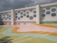 a white fence with colorful hexagons on it at the top of a hill