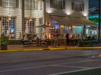 an outside cafe on a corner near the street at night with people sitting outside at tables