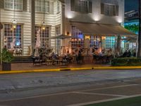 an outside cafe on a corner near the street at night with people sitting outside at tables