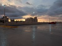 a red truck is parked in the rain at sunset on a street with no cars