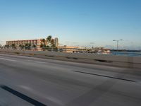 an expressway highway with cars travelling down the freeway and palm trees in the distance with buildings and buildings behind them