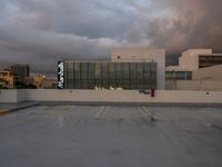 an empty parking lot with cars parked in it and sky and storm clouds overhead the place