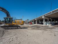 an excavating machine is on the dirt on a dirt patch in a construction area