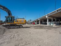 an excavating machine is on the dirt on a dirt patch in a construction area