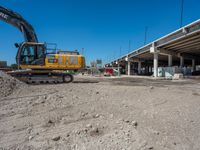 an excavating machine is on the dirt on a dirt patch in a construction area