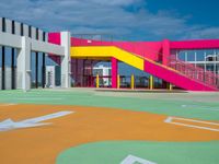 baseball field at school with brightly colored building behind it and stairs leading to each one