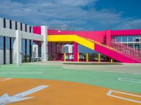 baseball field at school with brightly colored building behind it and stairs leading to each one