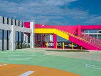 baseball field at school with brightly colored building behind it and stairs leading to each one