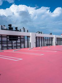 the empty tennis court is lined with different courts and markings of players on it and on the roof are red asphalt