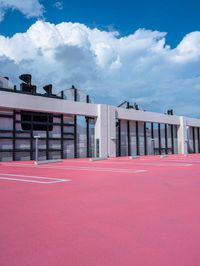 the empty tennis court is lined with different courts and markings of players on it and on the roof are red asphalt