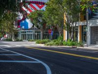 a tree lined street in front of a store with lots of flags flying in the background