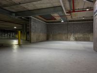 an empty parking garage with a parking meter above the fire hydrant and the light from above it