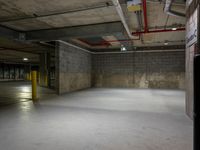 an empty parking garage with a parking meter above the fire hydrant and the light from above it