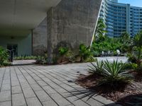 a building is in the distance and is seen from below, with an irregular - shaped concrete structure surrounded by plants