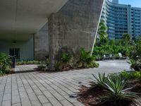 a building is in the distance and is seen from below, with an irregular - shaped concrete structure surrounded by plants