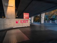 exit sign with bright red lights is set to a concrete wall by road side underpass