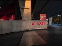 exit sign with bright red lights is set to a concrete wall by road side underpass