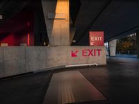 exit sign with bright red lights is set to a concrete wall by road side underpass