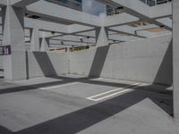 a concrete parking garage and a clear blue sky with white columns and beams above the concrete