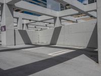 a concrete parking garage and a clear blue sky with white columns and beams above the concrete