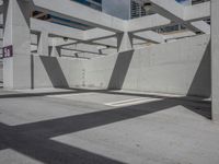 a concrete parking garage and a clear blue sky with white columns and beams above the concrete