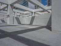 a concrete parking garage and a clear blue sky with white columns and beams above the concrete